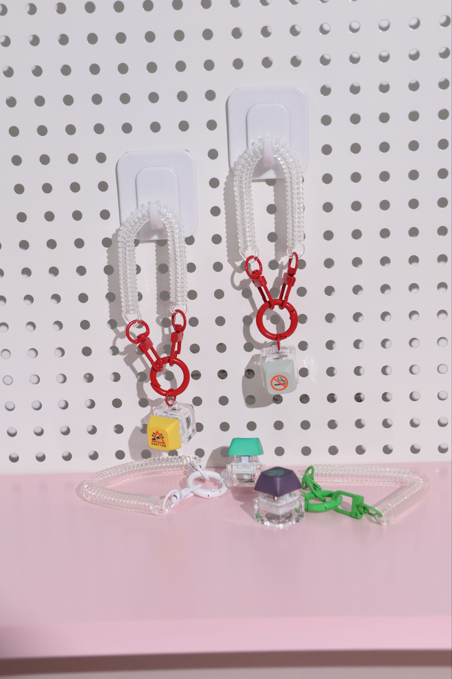 Set of keychains on a pegboard with a pink base