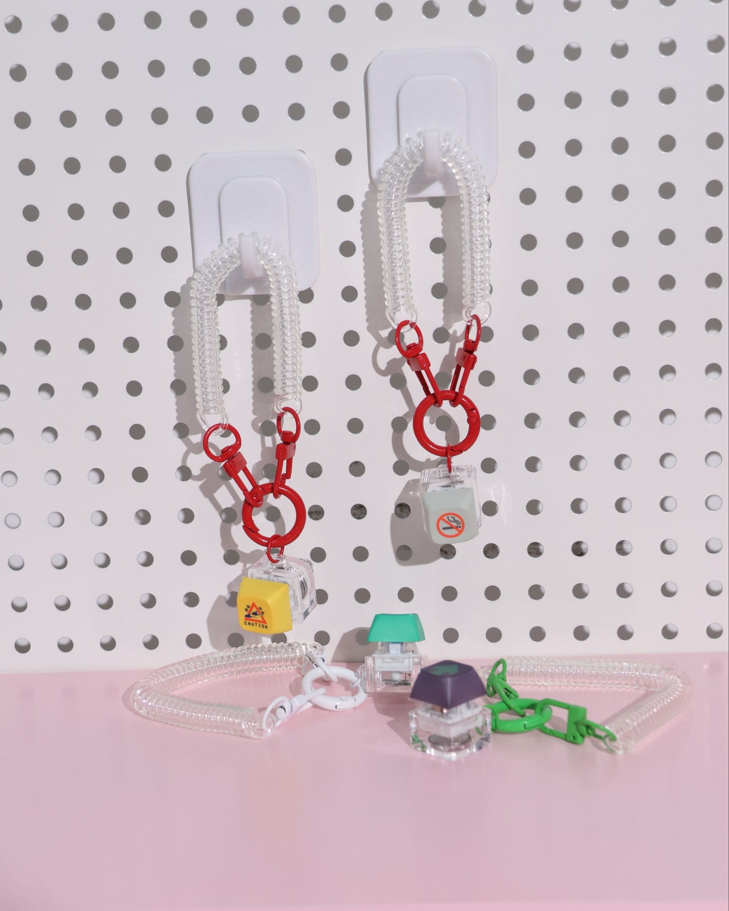 Set of keychains on a pegboard with a pink base