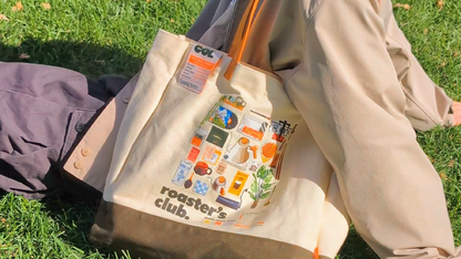 Person sitting on grass with a beige tote bag featuring 'roaster's club' branding.